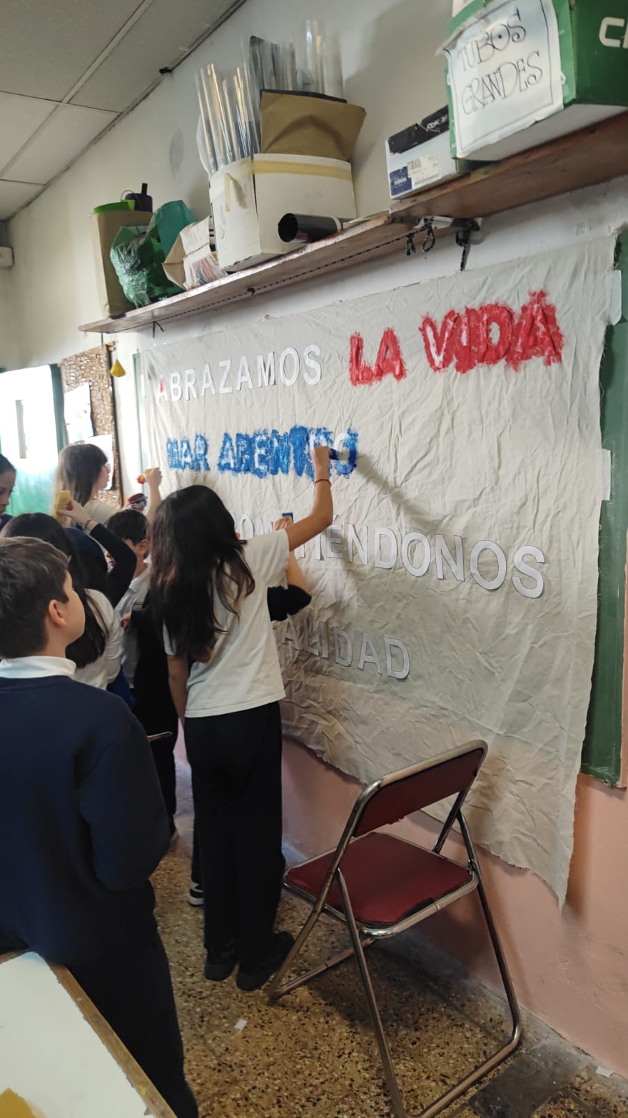Alumnos pintando la bandera del lema en el pasillo del colegio
